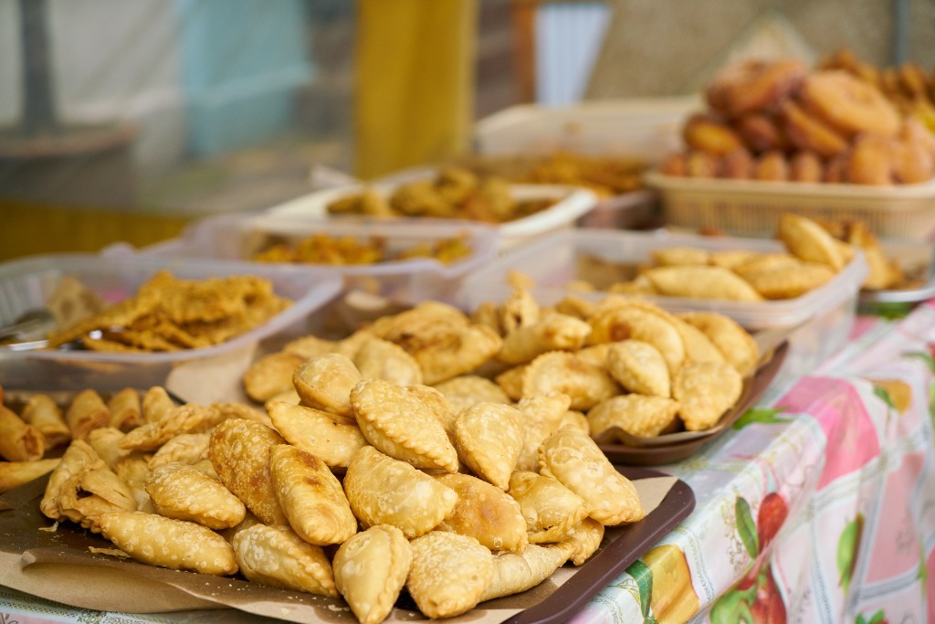 Travessa com coxinhas, quibes e salgados artesanais dourados e crocantes enfileirados prontos para entrega